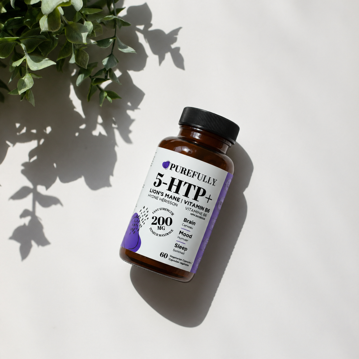 A bottle of Purefully 5-HTP+ dietary supplement placed diagonally on a white surface with soft shadows and green leaves in the top-left corner.